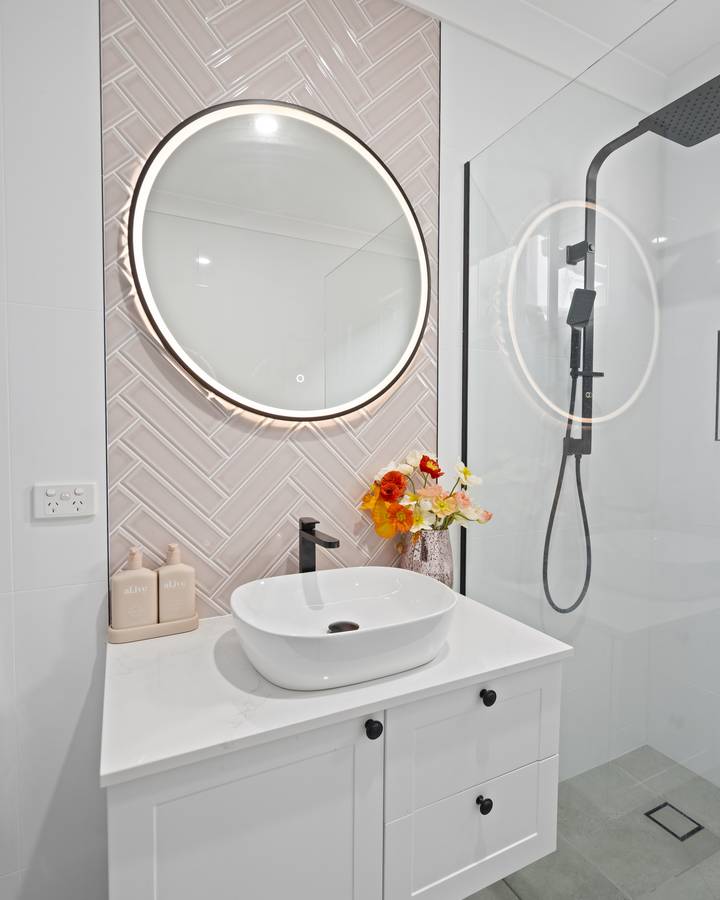 Main bathroom: Herringbone feature wall, backlit mirror, shaker vanity