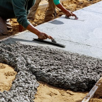 Contractors leveling and smoothing freshly poured concrete.