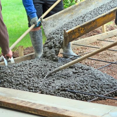 Pouring concrete for a driveway with workers smoothing the surface.