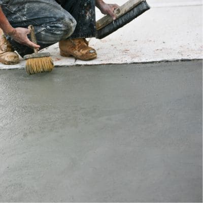 Contractor applying a broom finish to a concrete surface.