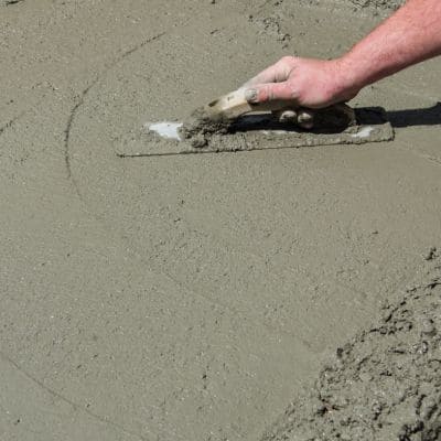 Contractor using a trowel to smooth and finish the surface of wet concrete