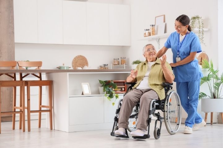 : A caregiver in scrubs navigating a bright kitchen area with a senior using high-quality manual wheelchairs.