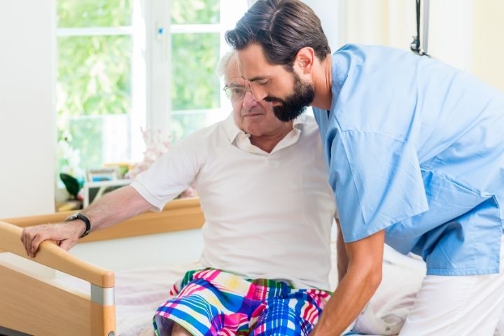 A caregiver assisting an older patient, demonstrating the choice of Electric hospital beds.