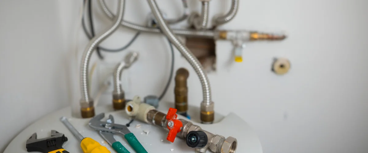 Plumbing tools and shut-off valve on top of a residential water heater.
