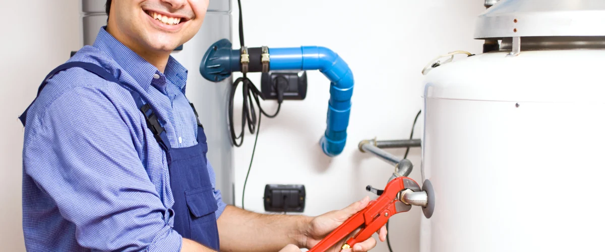 Plumber tightening connection on a residential water heater tank. Plumber tightening connection on a residential water heater tank.