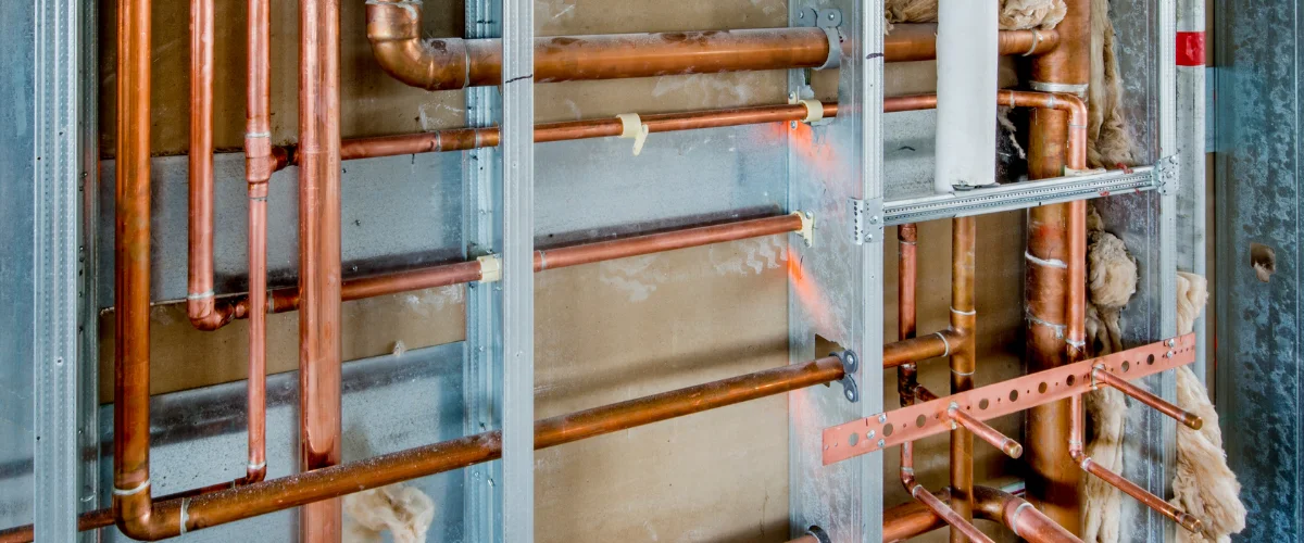 Copper plumbing pipes installed inside wall during construction.