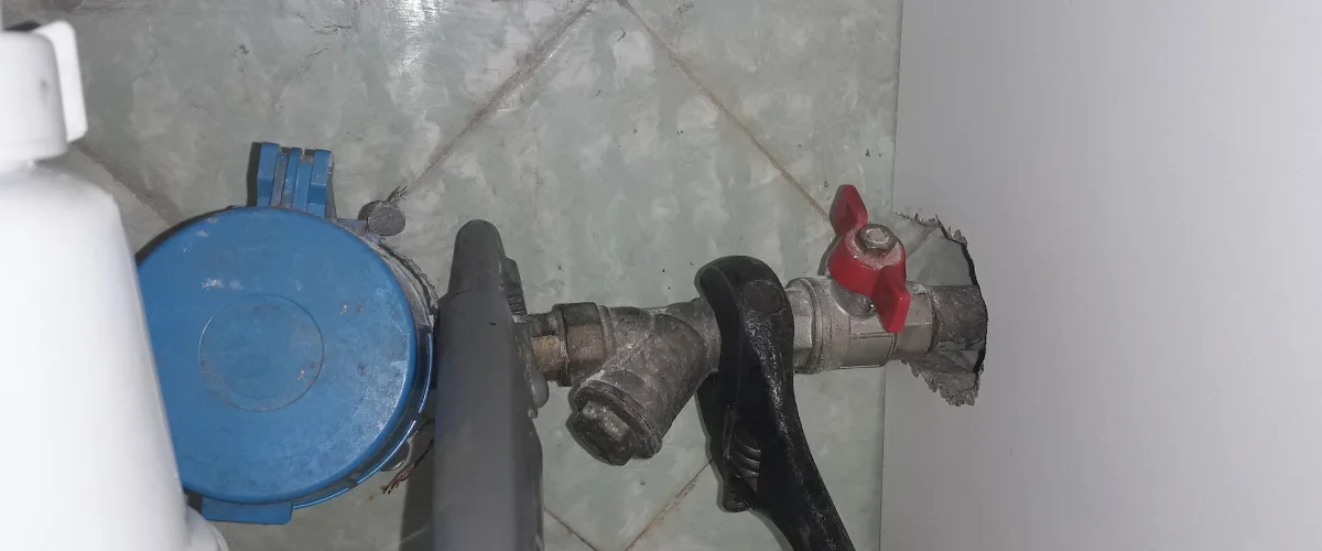 Adjustable wrench tightening plumbing valve connection.