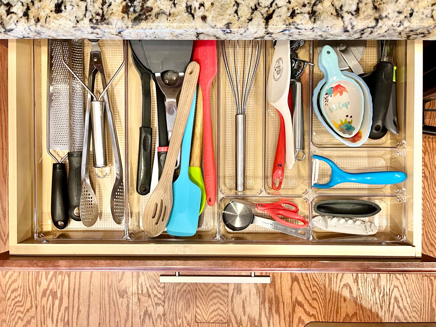 An organized kitchen utensil drawer with clear dividers An organized kitchen utensil drawer with clear dividers