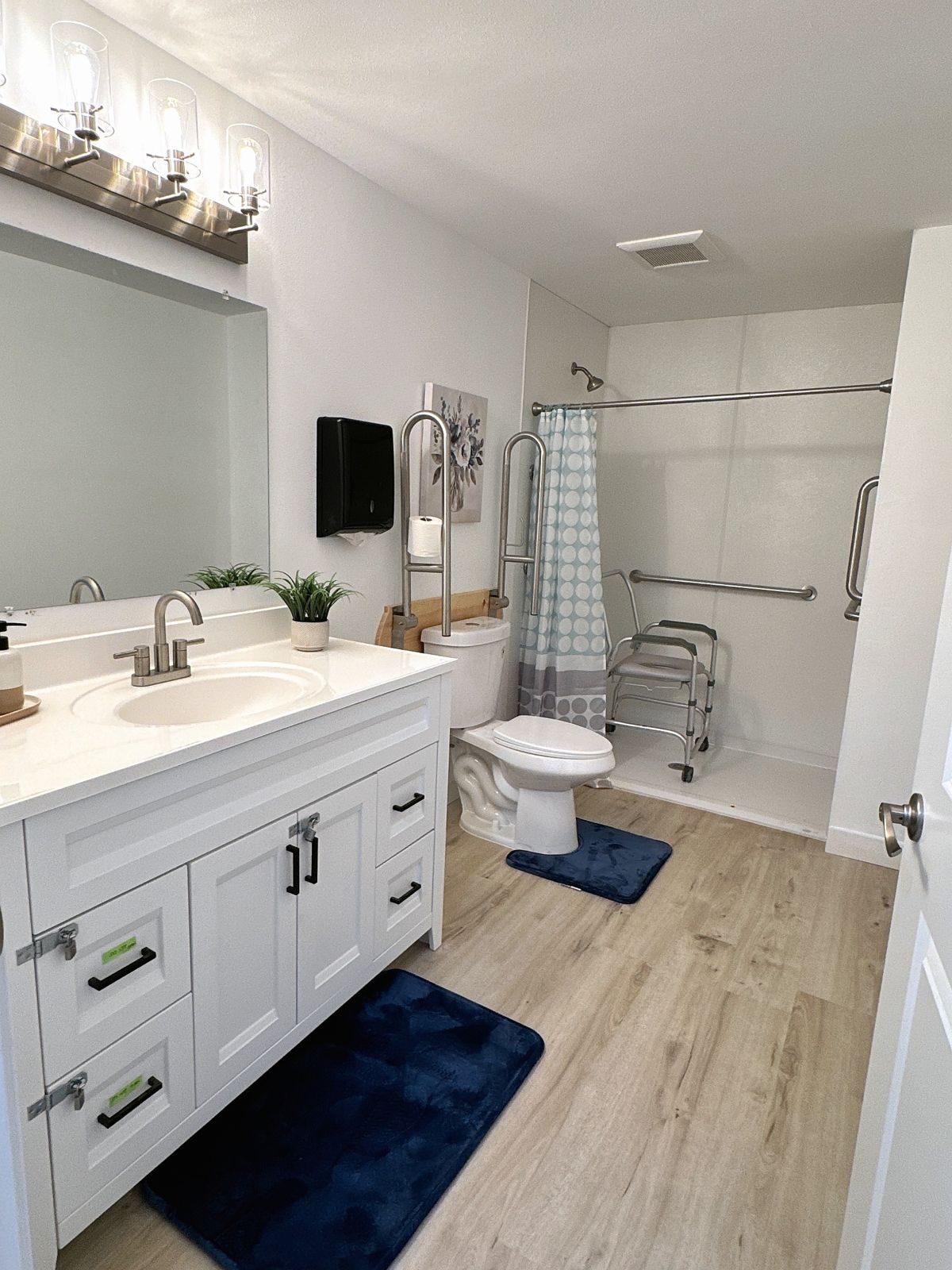 Bathroom with grab bars and a roll-in shower with shower chair