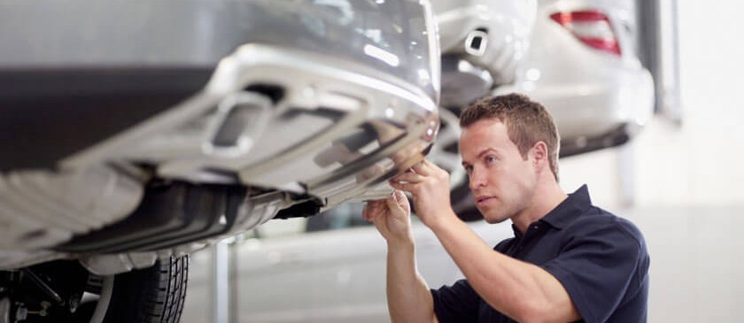 Technician working under a vehicle raised on a lift