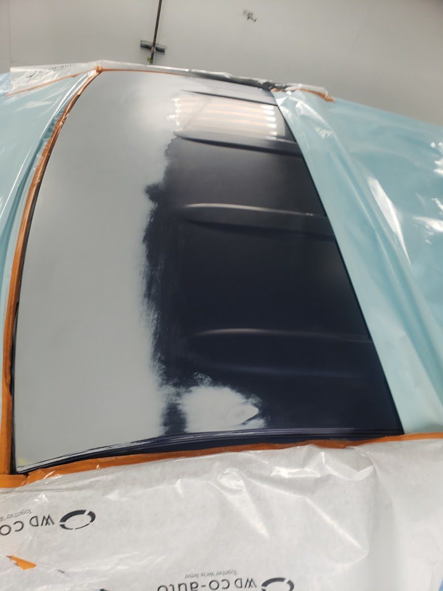 Vehicle panel masked with blue tape and paper, ready for paint
