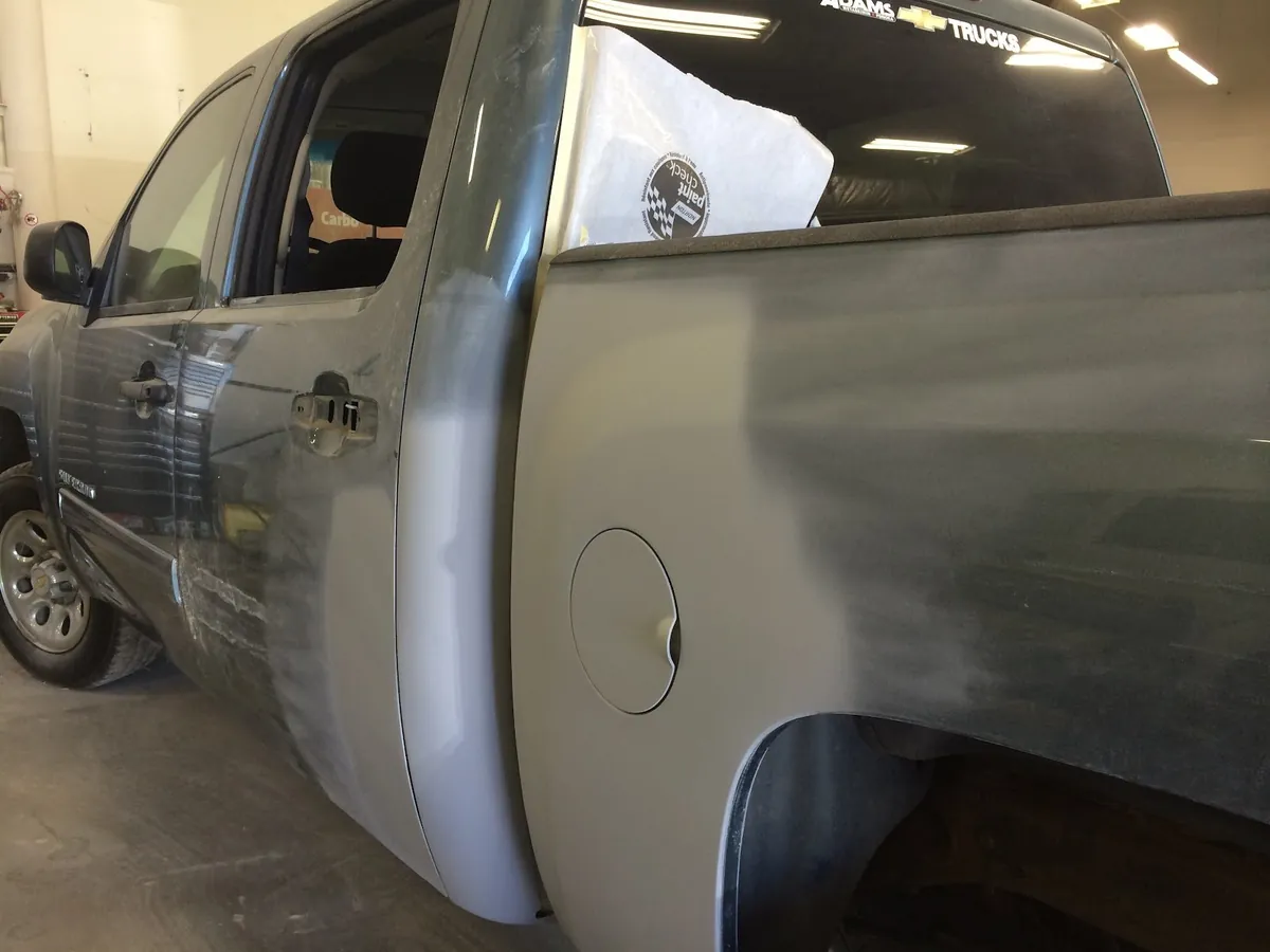 Rear quarter panel of a pickup truck sanded and primed during repair