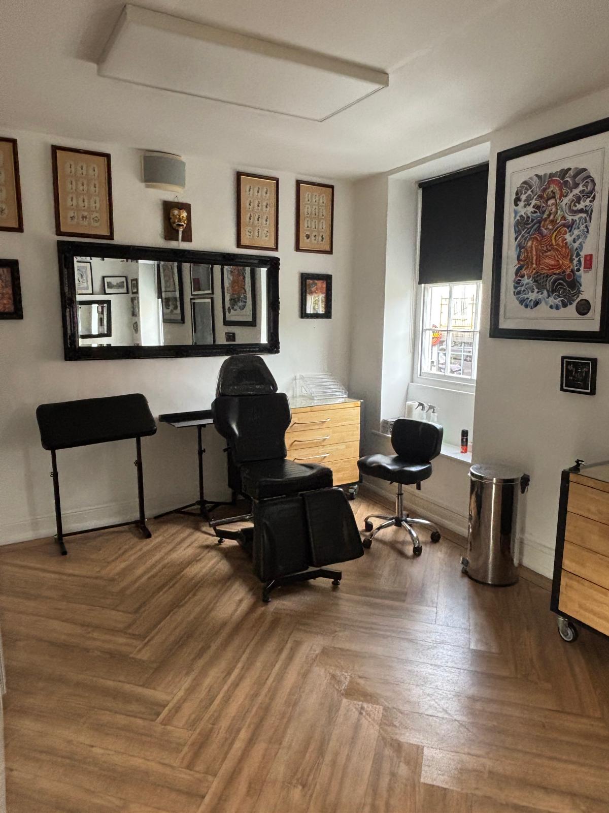 Tattoo room with treatment chair and framed artwork