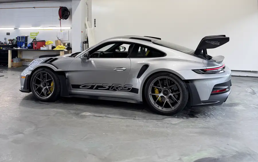 A silver Porsche GT3 RS in profile inside the AutoCore shop