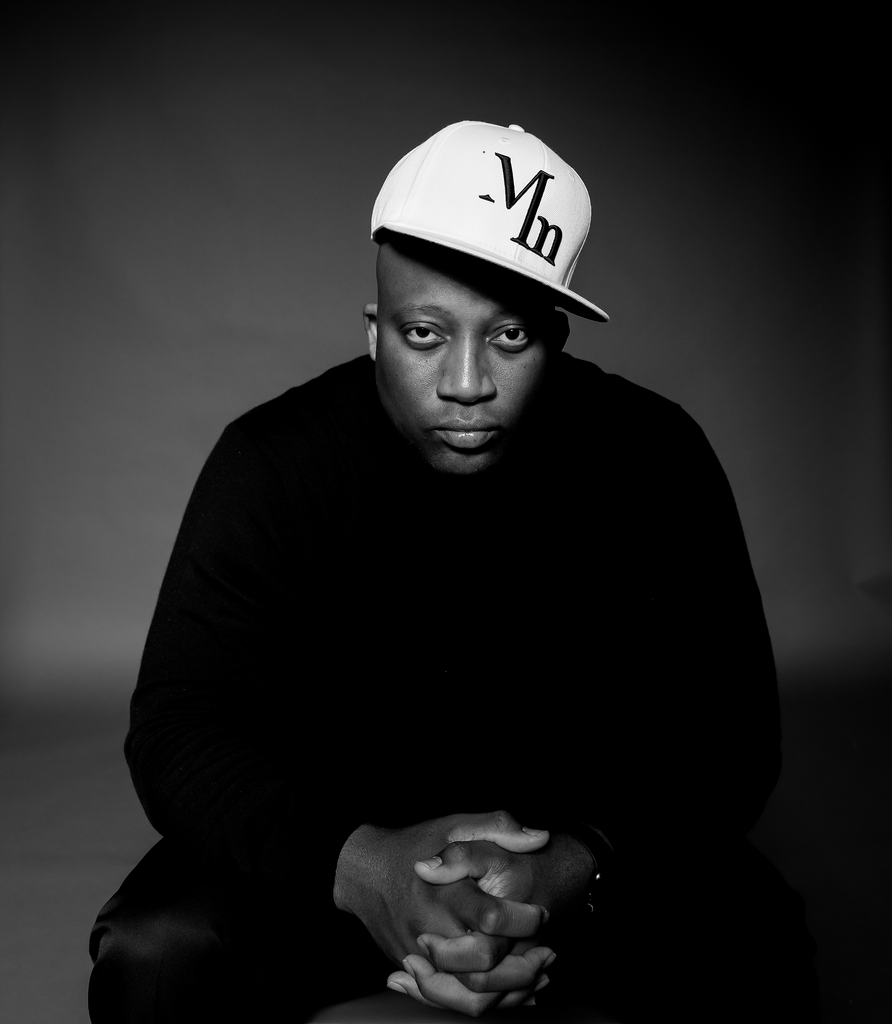 "Shaun Murphy, also known as Mister Motivation, seated confidently in black attire and branded white cap—motivational speaker and mindset coach portrait.