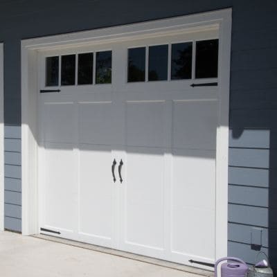 Elegant white carriage-style garage door with decorative handles