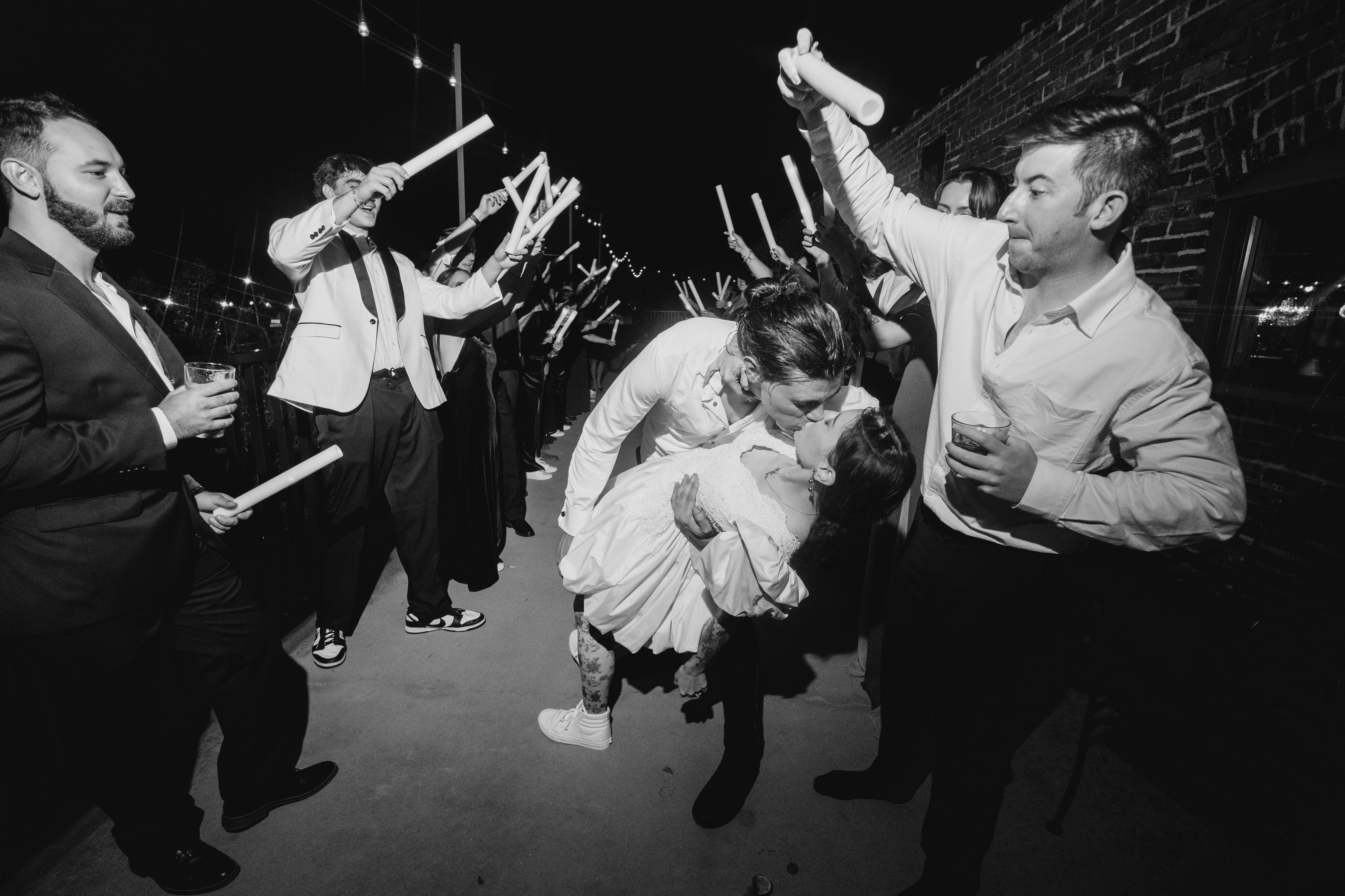 Couple kissing at their sparkler exit while guests cheer around them