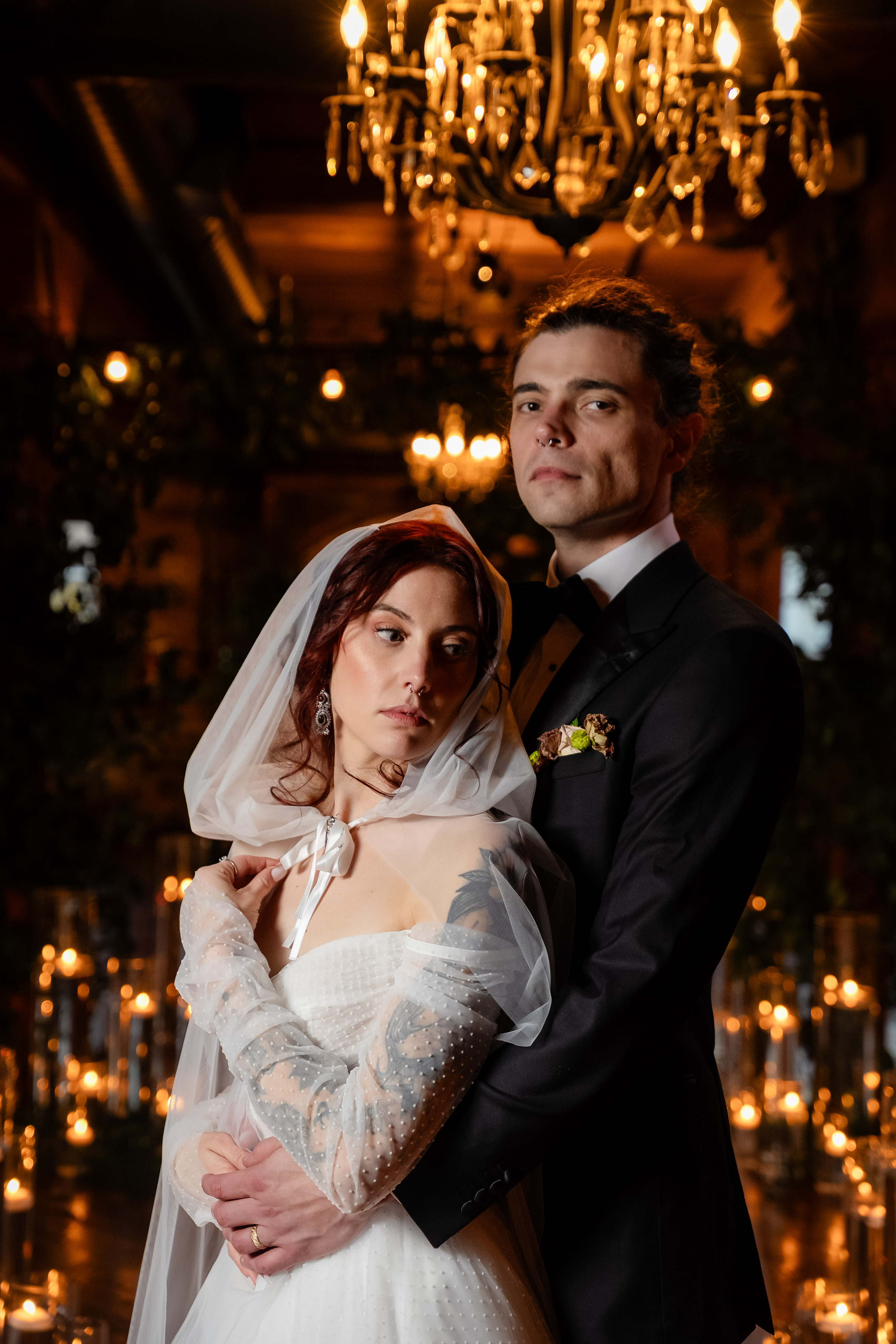 Couple standing together under chandeliers at their reception