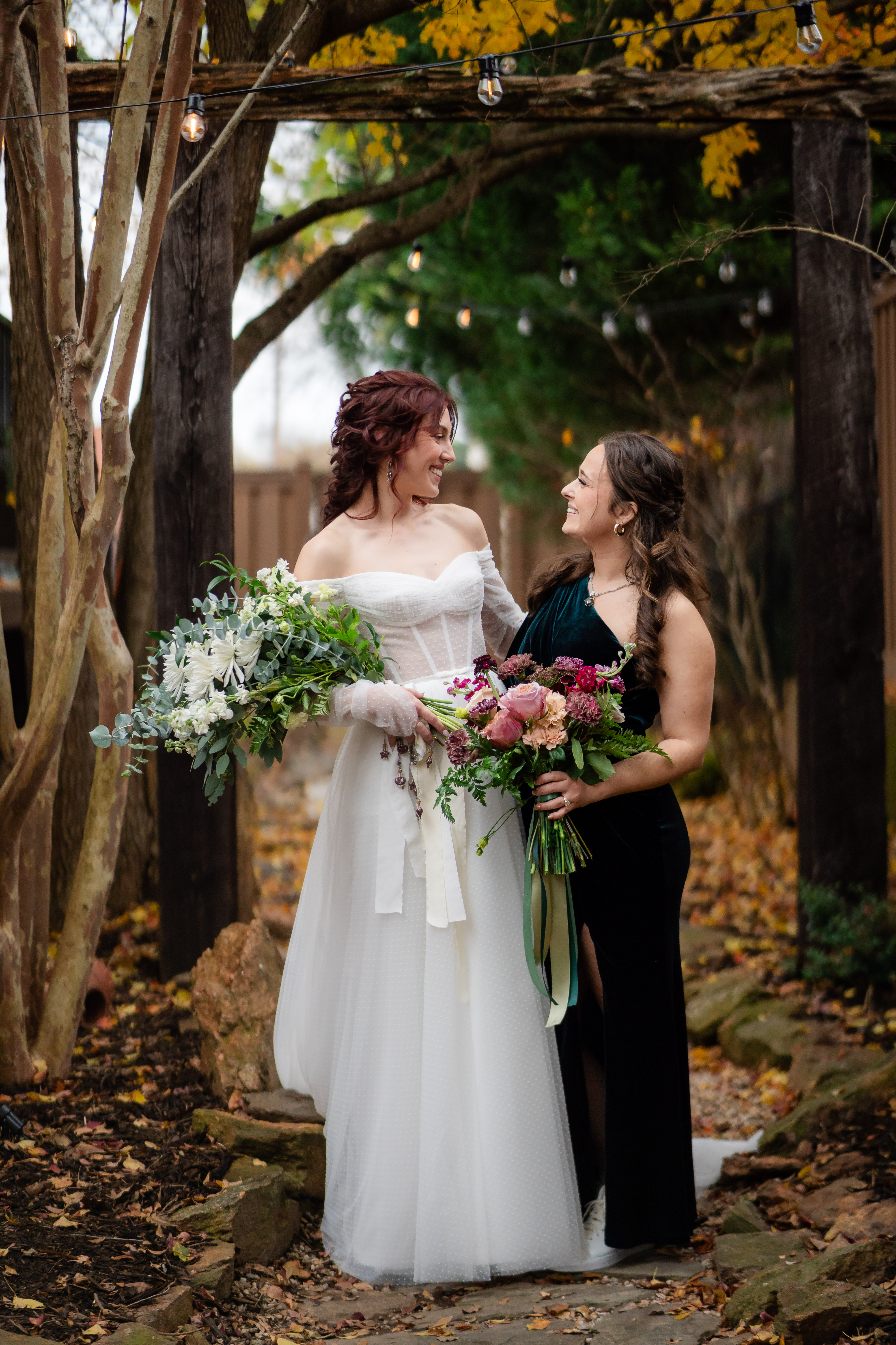 Couple under a vine arch holding a bouquet