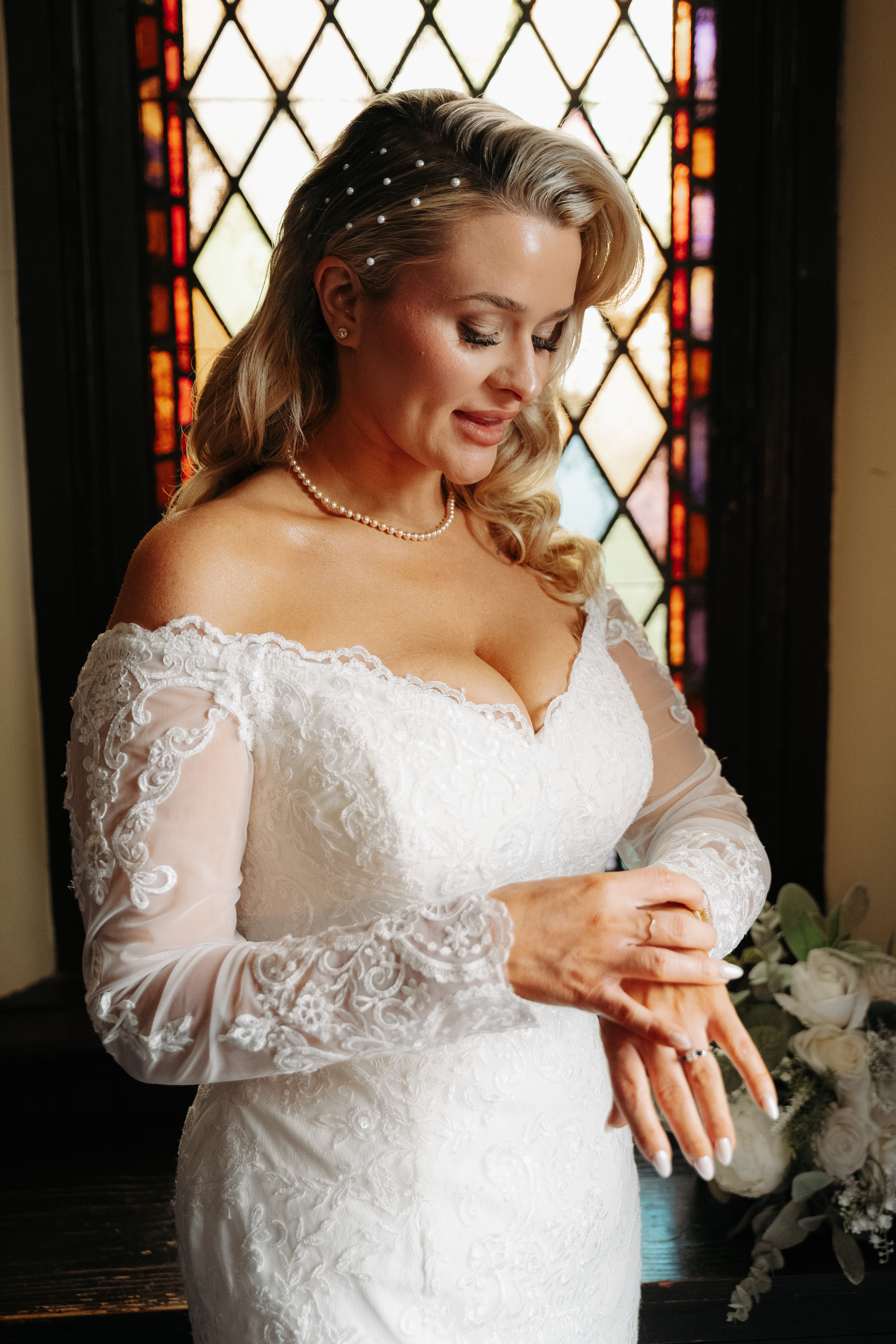 Bride in lace beside a leaded window