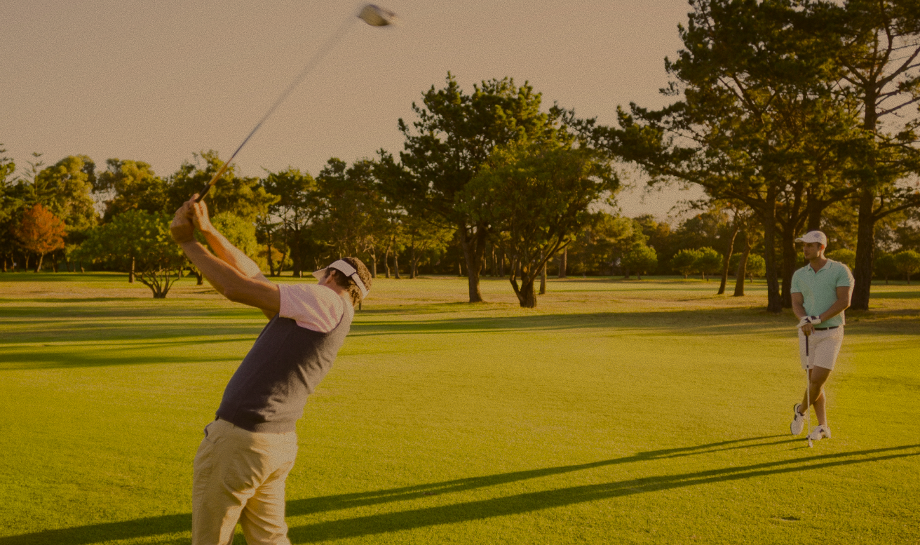 Golfer in mid-swing on the fairway at sunset