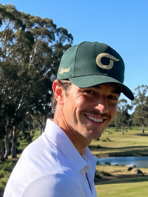 Golfer smiling in a green cap on the course