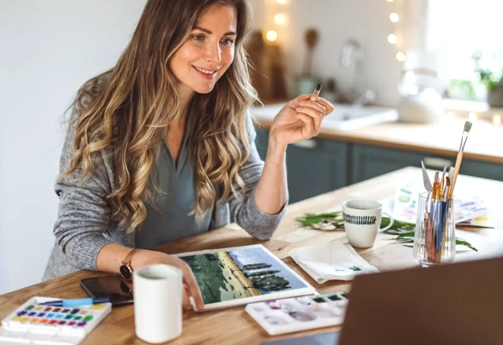 Woman smiling while painting a watercolor landscape during an online beginner-friendly painting course