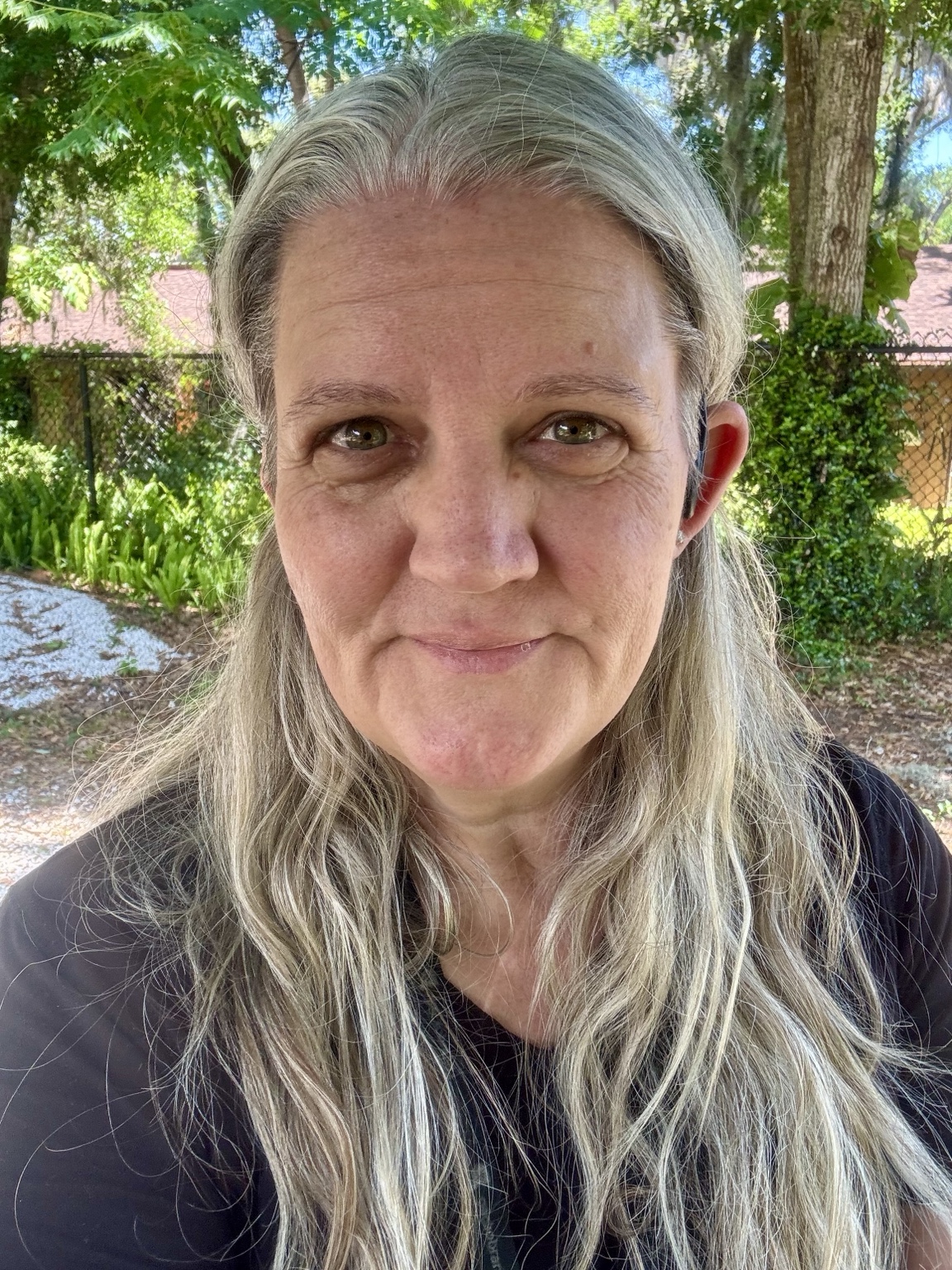 Becky outdoors among green trees