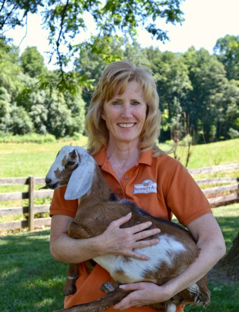 picture of Mary carrying a goat on her farm