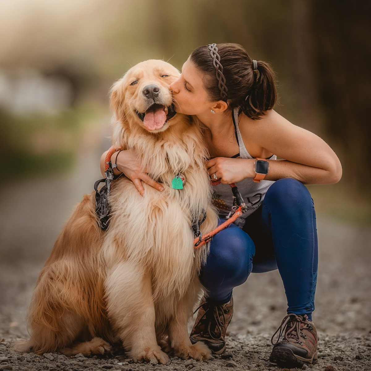 Woman embracing and kissing her golden retriever