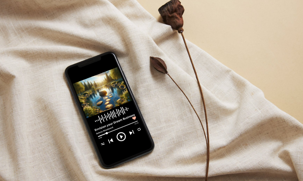 A phone on soft linen playing the Envision Your Dream Business guided meditation by Selena Woodward