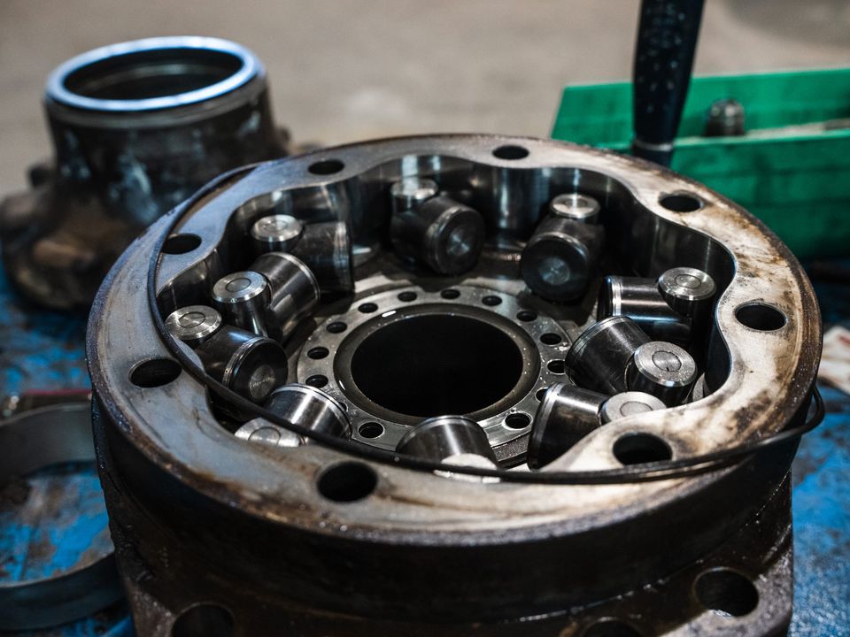 Close-up of a disassembled hydraulic motor housing with its pistons, on a blue-stained workbench