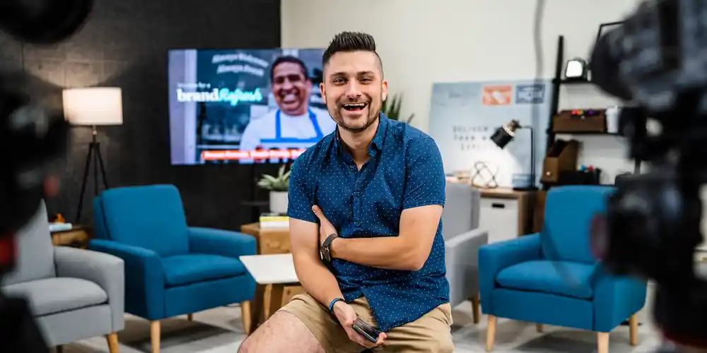 Jordan on set in a studio, with a Brand Refresh slide on the screen behind him