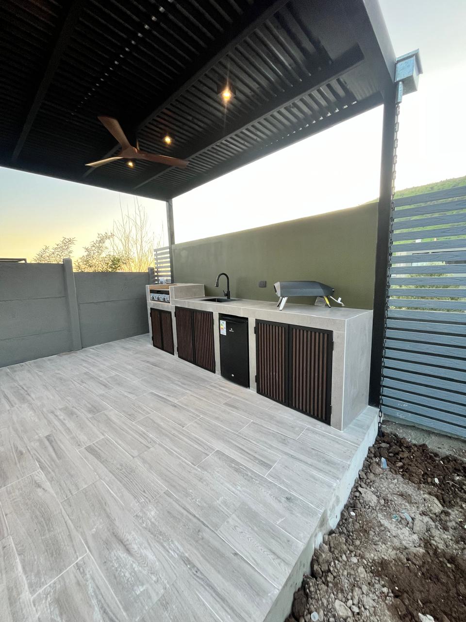 Terraza con pérgola y cocina exterior construida por Edificart