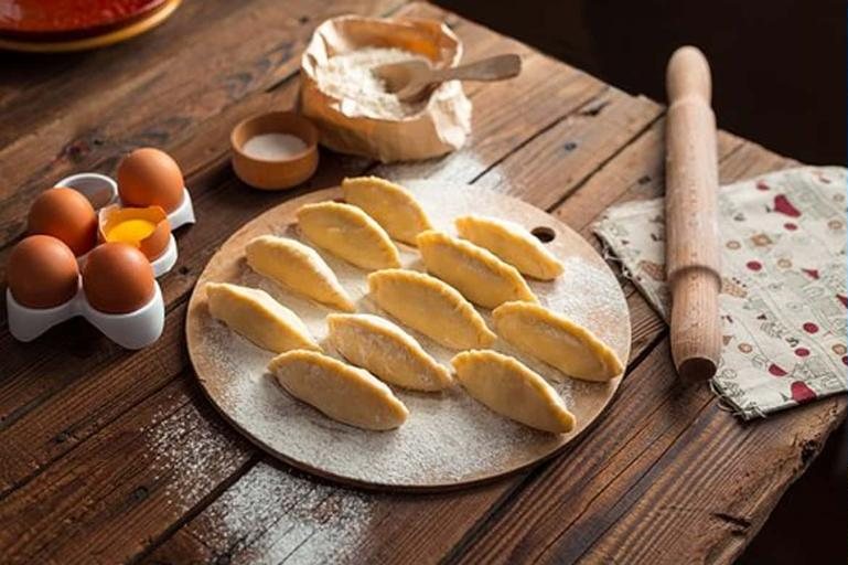 Handmade pasta on a floured board beside eggs and a wooden rolling pin