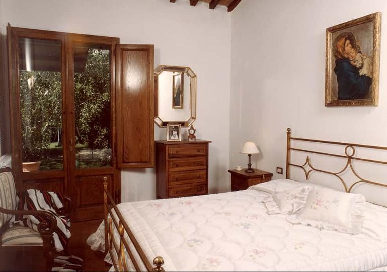 Glicine bedroom with a brass double bed and garden doors