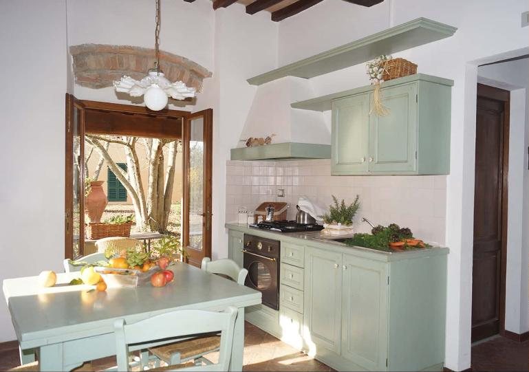Rosa kitchen and dining table in pale green, with doors open to the garden