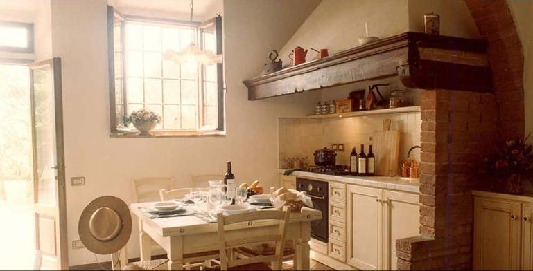 Rosmarino kitchen with a brick hearth and a table laid with wine and bread