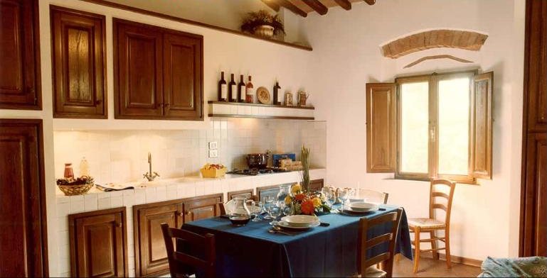 Torretta kitchen with dark wood cabinets and a blue-clothed dining table