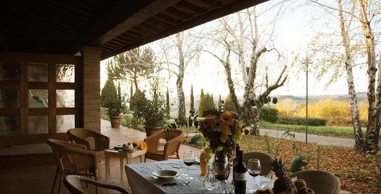 Ulivo's covered patio with a table set with wine and flowers, looking out over birch trees