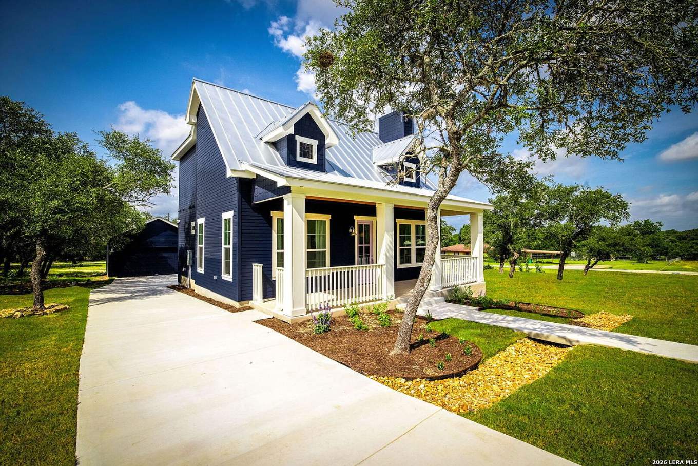 Navy craftsman cottage with a wide front porch under live oaks