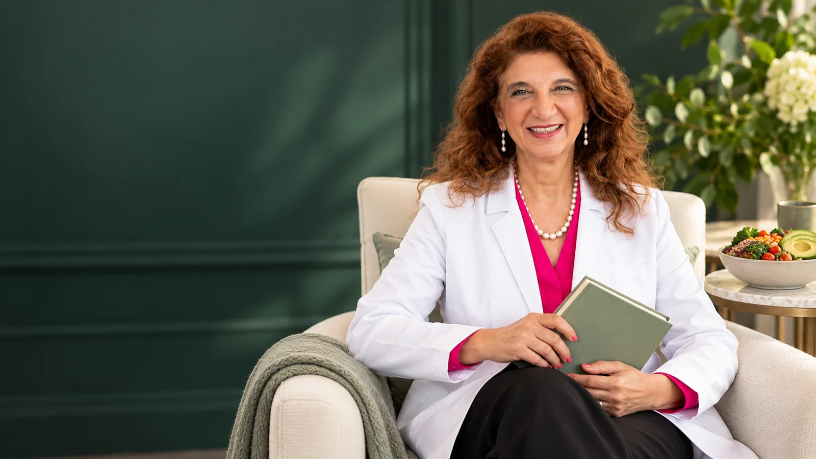 Dr. Dalal Akoury holding an unlettered book beside a healthy meal at AWAREmed in Johnson City, Tennessee.