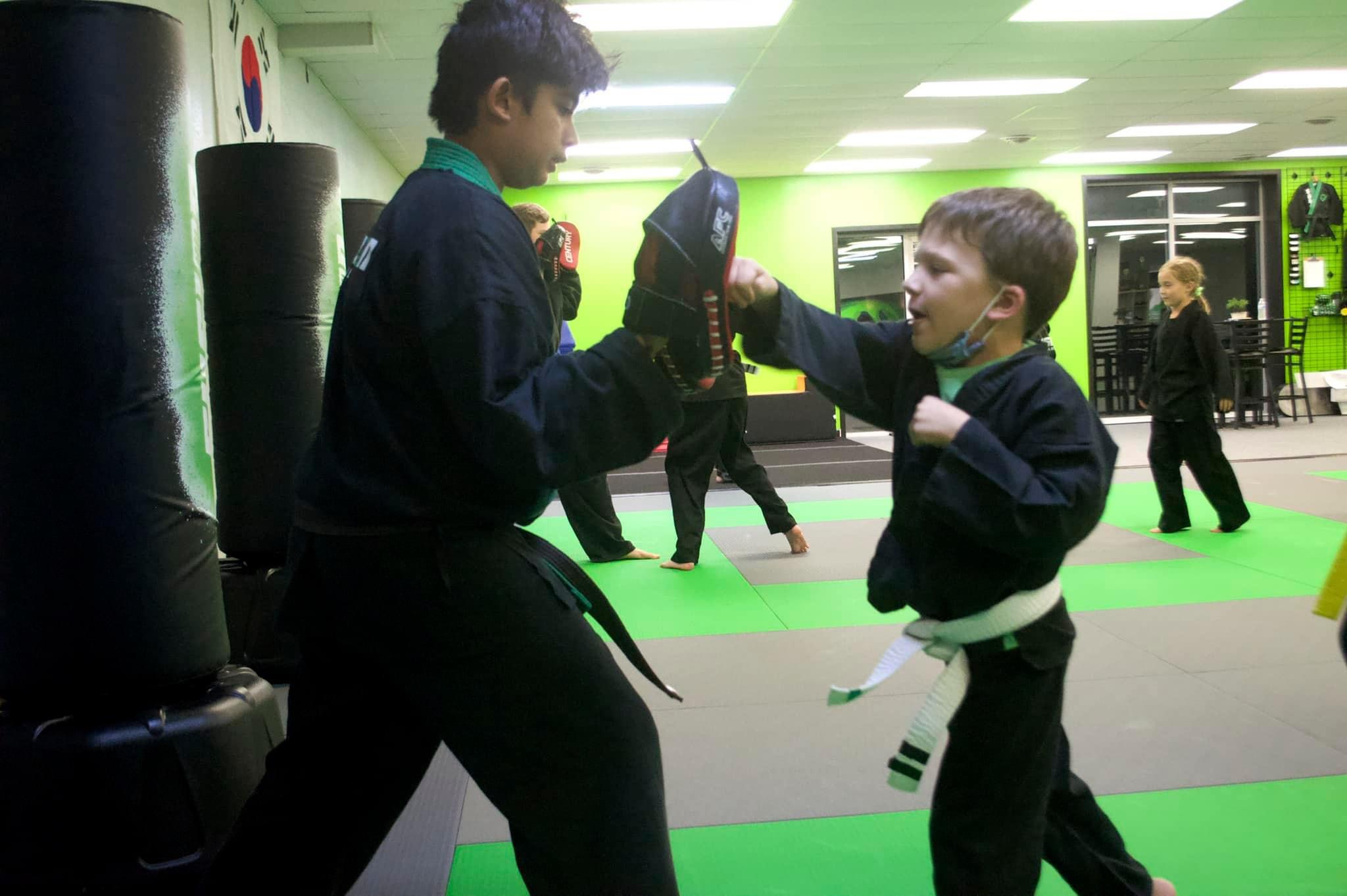 Kids practicing punching drills on pads at Fusion Martial Arts