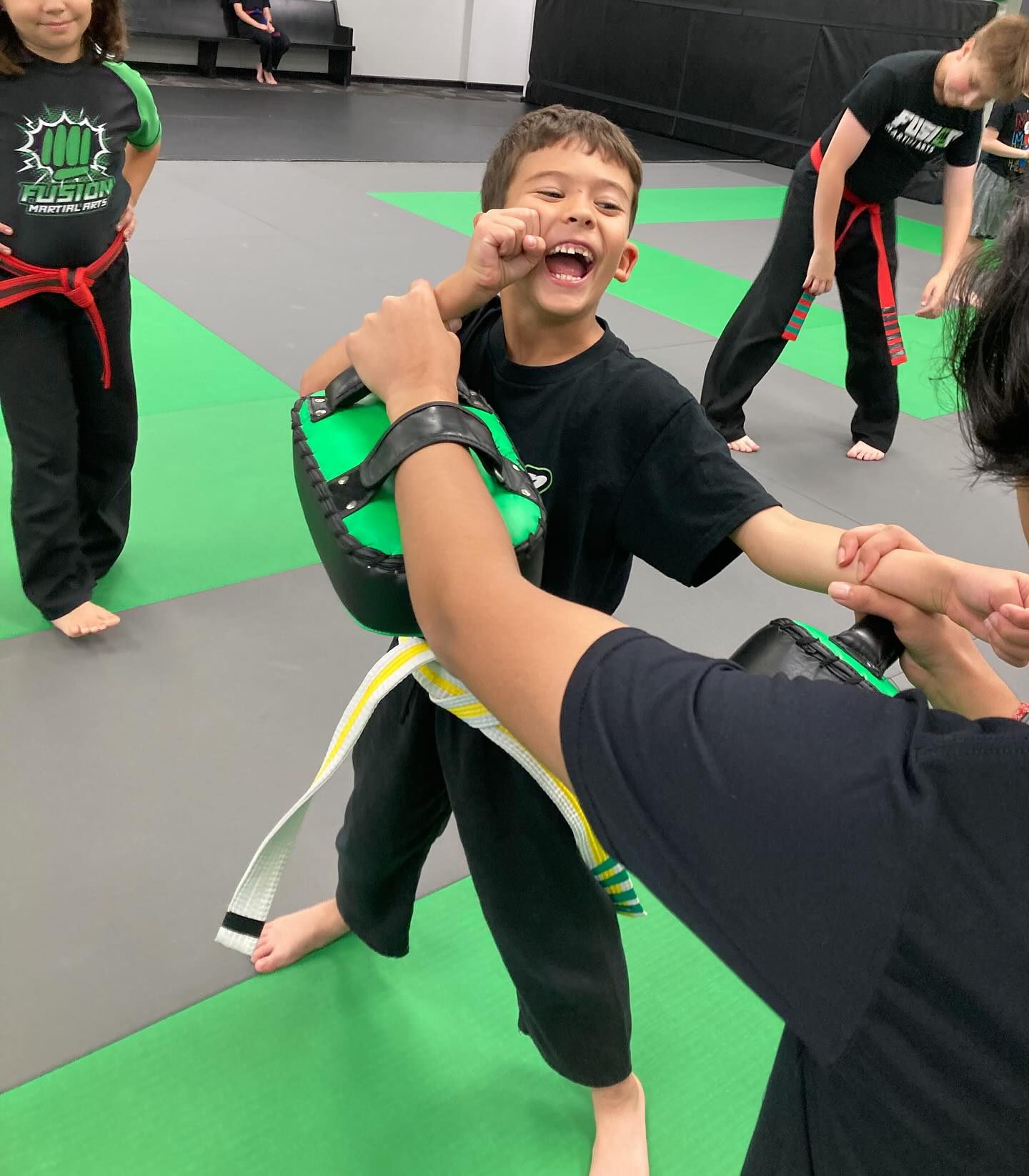 Young student training on pads during class at Fusion