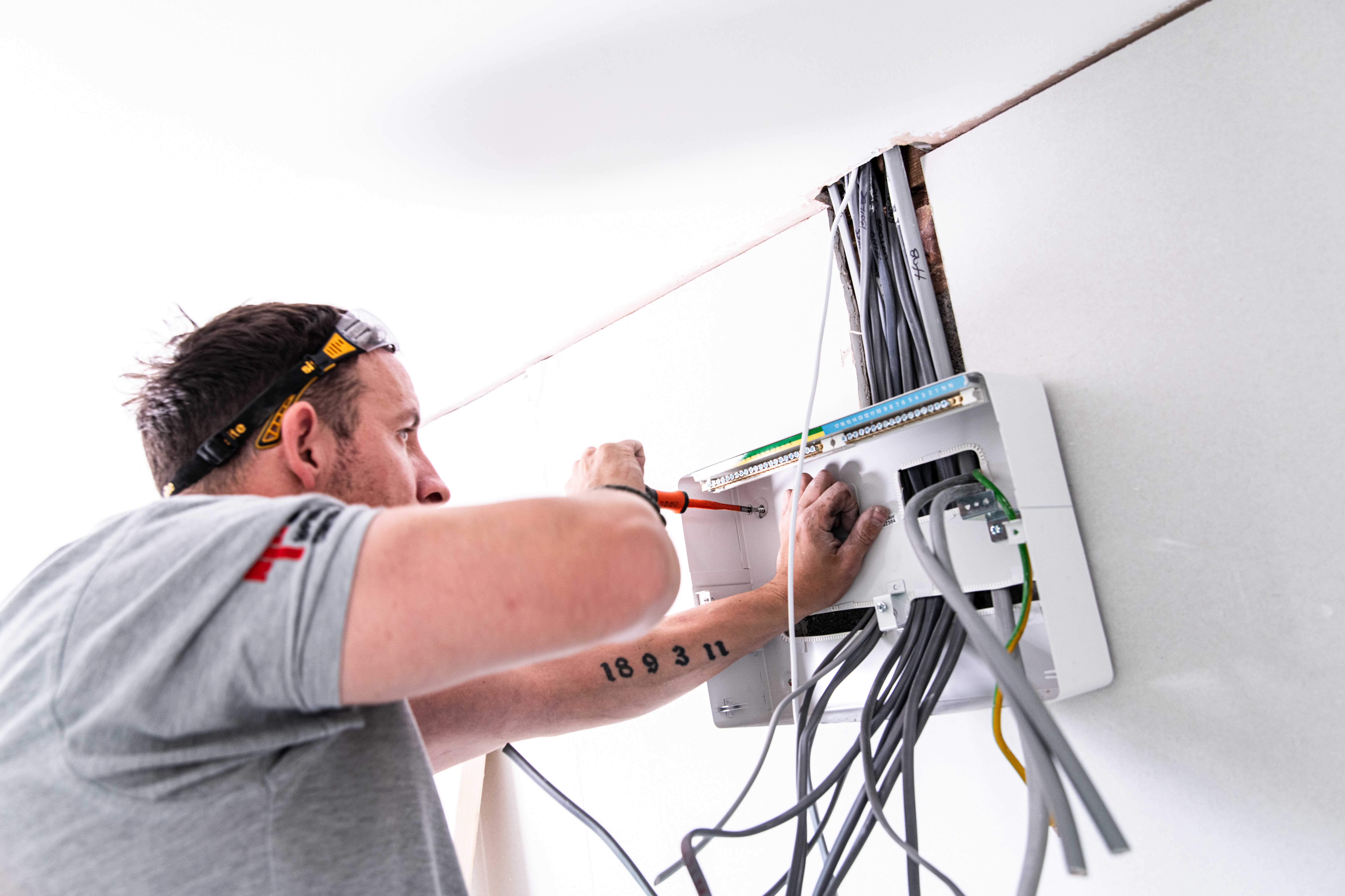Qualified electrician carrying out electrical safety testing at a consumer unit