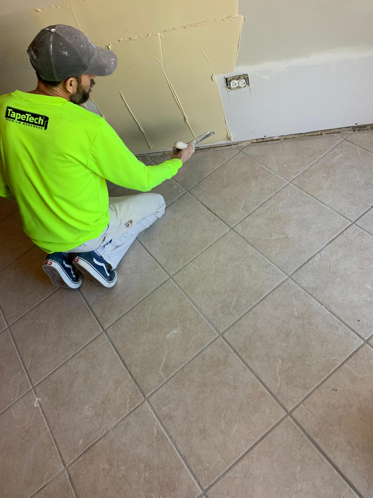 Worker patching drywall to a smooth finish