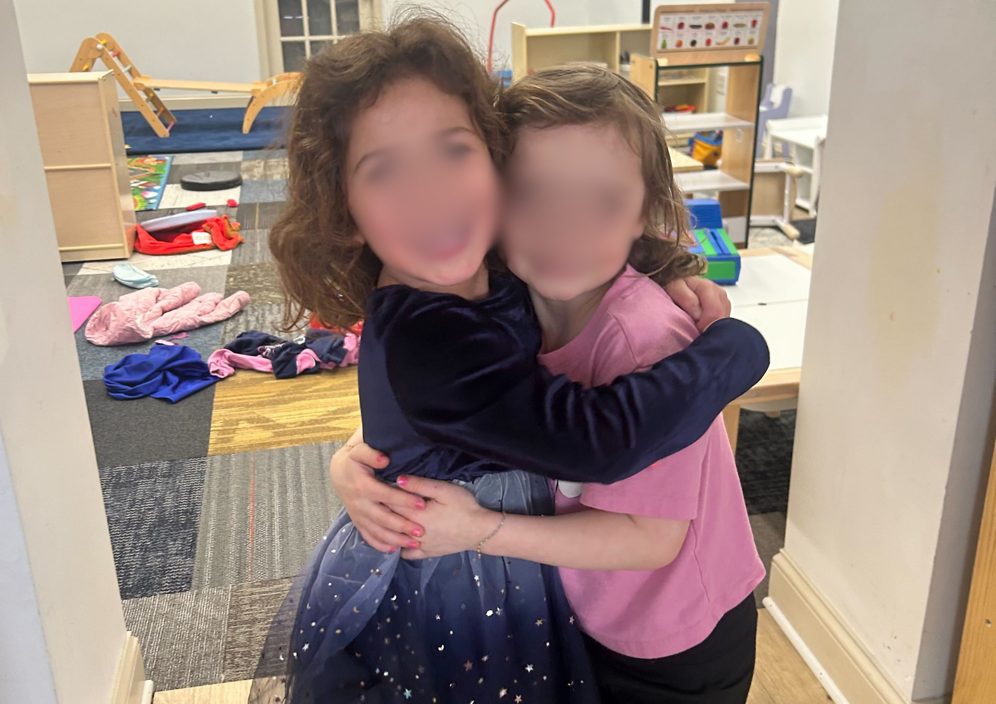 Two young girls sharing a warm hug, smiling and showing friendship and connection.