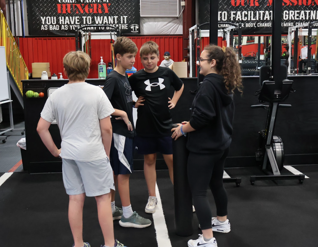 Young athletes talking with a Varsity House coach between combine drills
