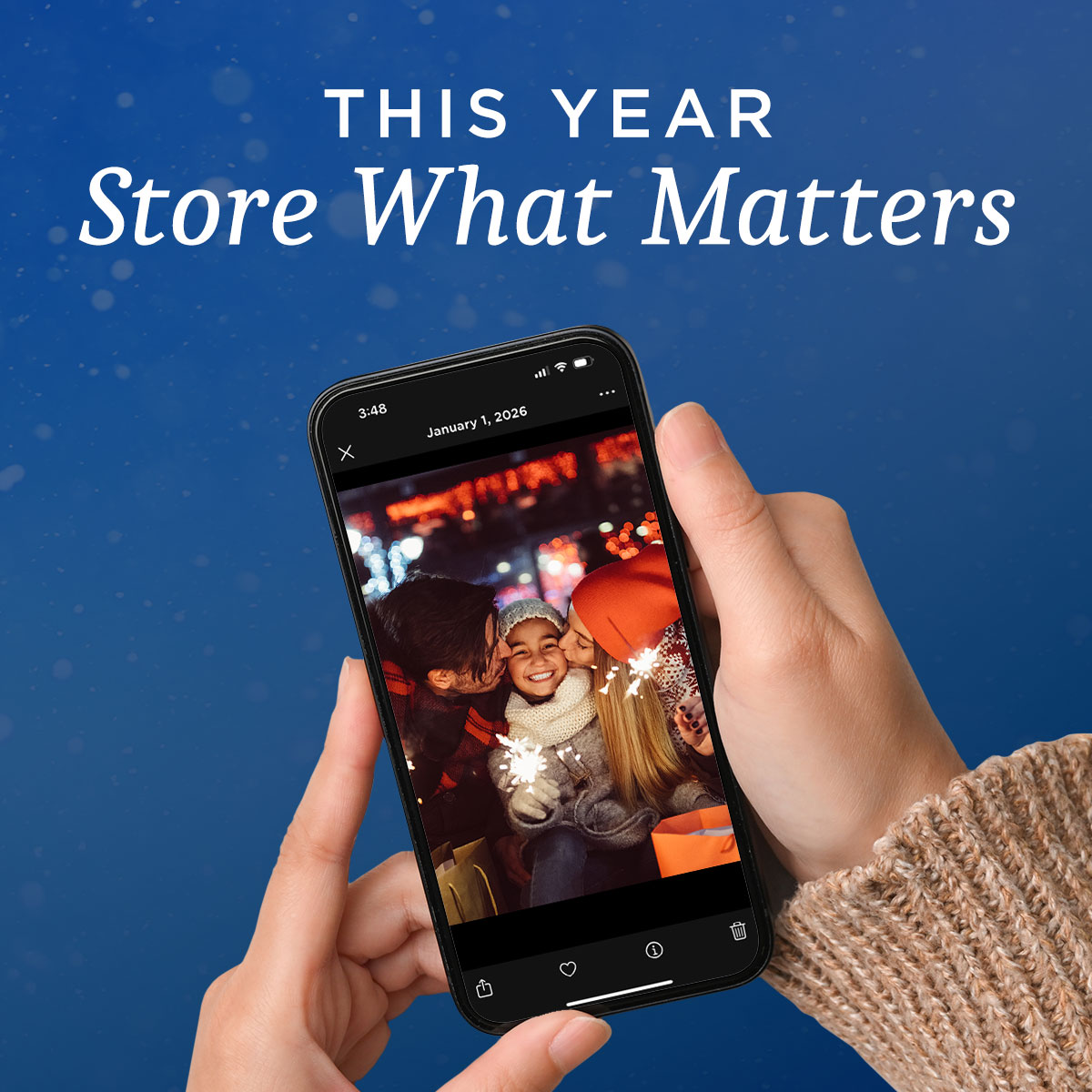 Hands holding a smartphone displaying a joyful family photo with sparklers, set against a blue background. Large text at the top reads “This Year Store What Matters,” emphasizing the importance of preserving meaningful memories.