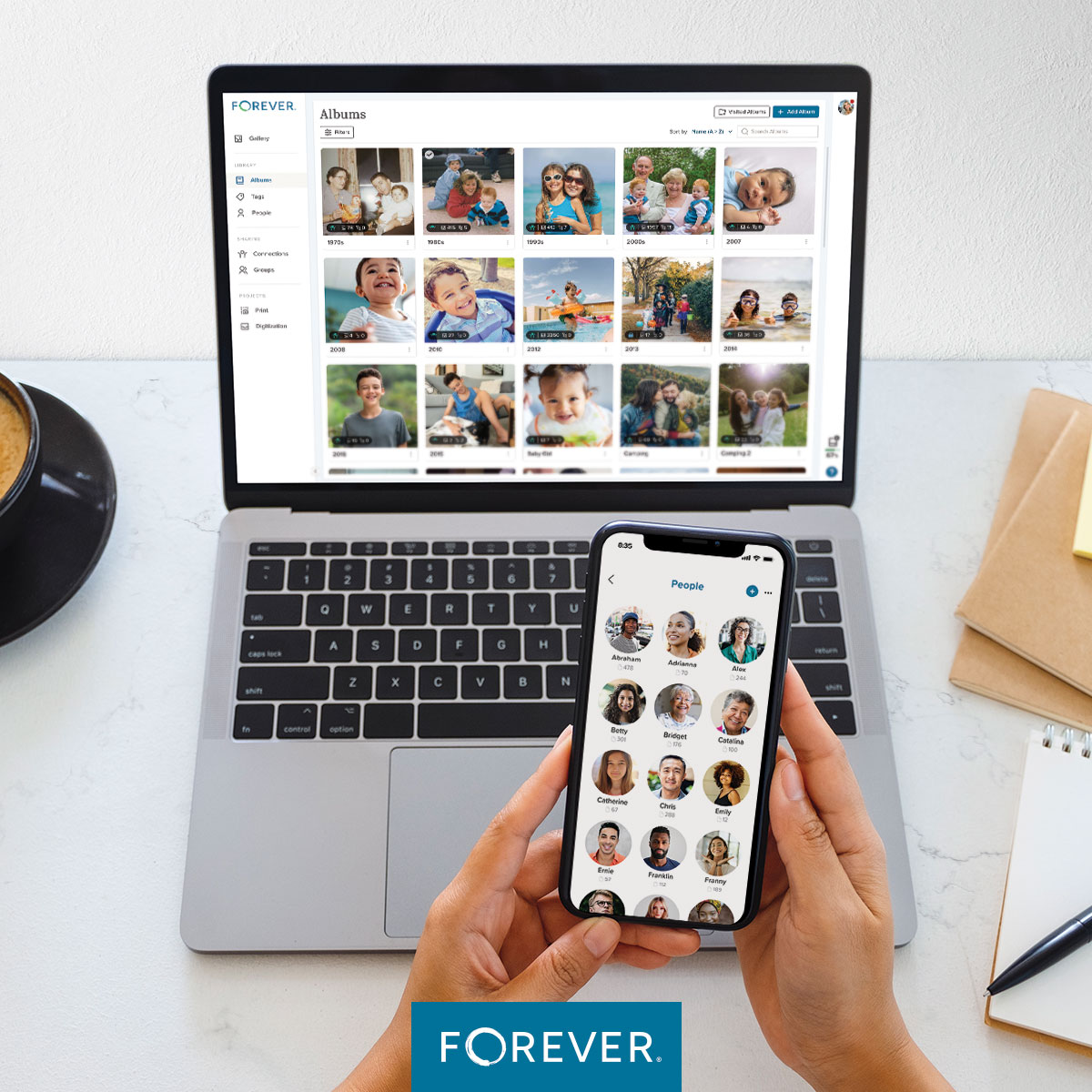 Person holding a phone with FOREVER photo organization app while viewing organized photo albums on a laptop screen